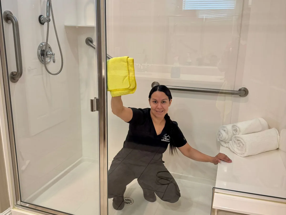Anna's Housekeeping cleaner polishing a glass shower door in a West Valley Arizona home